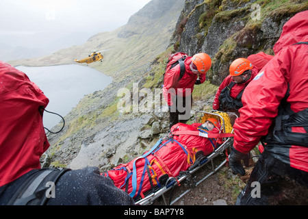 Ein Spaziergänger mit einer zusammengesetzten Bein Fraktur wird von Langdale Ambleside Bergrettung in leicht Gully auf Pavey Arche behandelt. Stockfoto