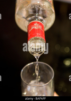 Smirnoff Vodka wird aus einer Flasche auf ein Glas mit Eis gegossen. Stockfoto