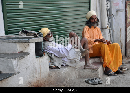 Ein Alter Mann sitzt companionably mit einem Sadhu in Udaipur, Indien Stockfoto
