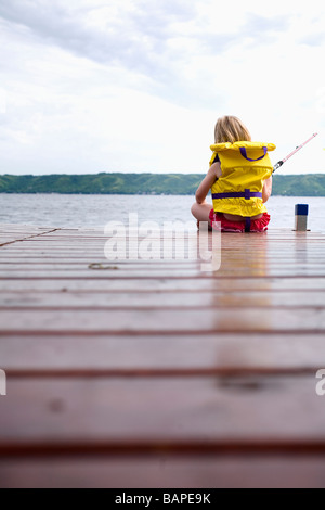 Junge Mädchen tragen Rettungsring Fischerei vor Ende des Dock am Echo Lake, Saskatchewan, Kanada Stockfoto