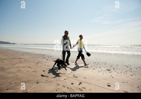 Ein junges Paar hand in hand gehen mit ihrem Hund an Newgale Strand Pembrokeshire Coast National Park Wales Sommernachmittag Stockfoto