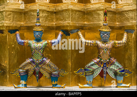 Mythologische Dämonen unterstützen einen großen vergoldeten Chedi oder Stupa im Wat Phra Kaeo, Bangkok, Thailand Stockfoto