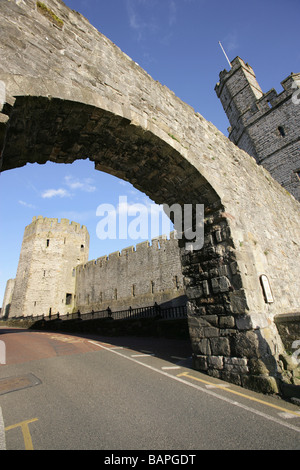 Stadt von Caernarfon, Wales. Caernarfon Stadtmauer Bogen am Stift Deitsh mit Eagle Tower und Wasserturm im Hintergrund. Stockfoto