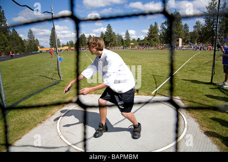 Eine Mittelschule jungen Diskuswurf während einer Schule Leichtathletik treffen sich auf dem Gebiet der örtlichen Realschule, Bend, Oregon. Stockfoto