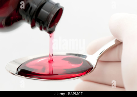 Löffel Hustensaft Erfülltsein durch Person mit Latex Handschuhen auf weißem Hintergrund Stockfoto