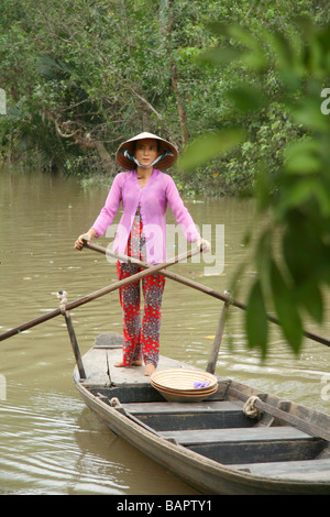 Eine Frau rudert ein hölzernes Boot entlang der Autobahnen Wasser des Mekong-Delta in Vietnam Stockfoto