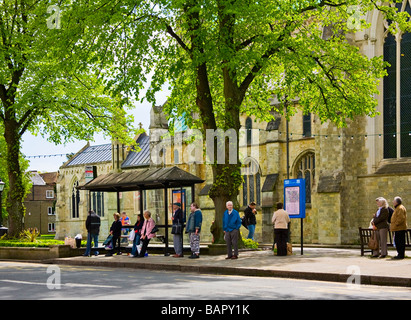 Die Menschen warten auf einen Bus in West Street, Chichester mit Chichester Cathedral im Hintergrund. West Sussex, UK Stockfoto