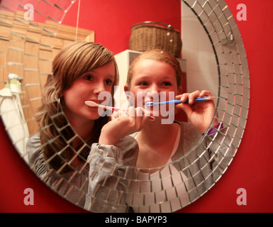 2 Mädchen im Teenageralter Bürsten es Zähne im Spiegel Stockfoto