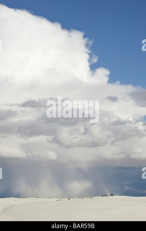 Reiter und Pferde auf Dünen in White Sands National Monument unter Gewitterhimmel nach Regenfällen Stockfoto