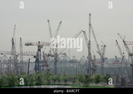 Viele Kraniche in Singapur arbeiten fieberhaft Gebäude ein neues MegaCasino mit Frachtschiffen hinter durch noch mehr Kräne entladen. Stockfoto