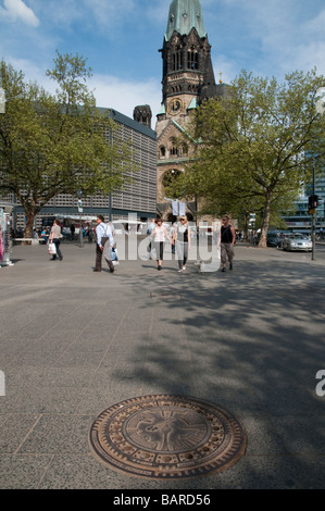 Deutschland Berlin Kufurstendamm shopping Bereich Ansicht mit Kaiser Wilhelm Gedachtnis Kirche Denkmal in Bkgd und Abwasser Deckel in Frgd Stockfoto