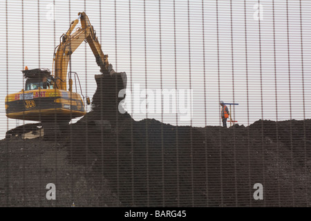 Ein Baumeister mit Blick auf einen Bagger, Identität des Mannes nicht erkennbar und ein Teil der Olympic Development bei Temple Mills Lane. London.UK. Stockfoto