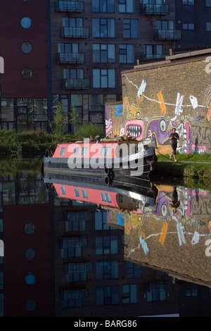 Ein Grachtenboot auf Fluss Lee, high-Rise Wohnungen, eine weibliche Jogger, Graffiti mit deren Spiegelung in den Fluss. Stockfoto