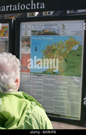 Frau touristischen lesen Informationstafel und Karte der Grafschaft Donegal in Donegal Town, Irland Stockfoto