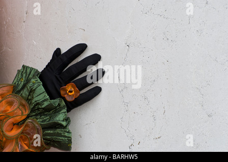 Nahaufnahme einer Hand mit orange Blume Ring von Venedig Verkleidung vor eine Wand Blume Ring von Venedig Verkleidung vor einer Wand Stockfoto