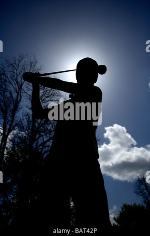 Silhouette der junge Golfer halten einen Golfclub Treiber zu schwingen, den Ball zu schlagen, gegen blauen Wolkenhimmel Stockfoto