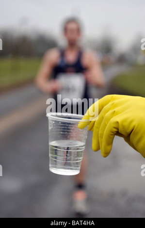 männliche Läufer in Langstrecken-Straßenrennen Abholung Trinkwasser aus behandschuhte hand Stockfoto