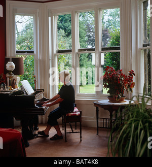 Dame spielen einen Steinway Stutzflügel Klavier infront von einem Erker Stockfoto