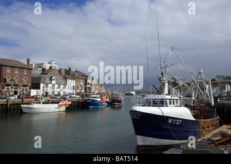 Gewitterwolken wälzen sich der Fischereiflotte vertäut im Hafen von Weymouth in Dorset, England. Stockfoto