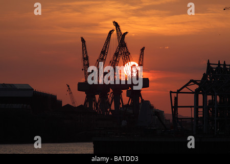 Sonnenuntergang über der alten Krane auf BAE Systeme Werft neben dem Fluss Clyde in Govan, Glasgow, Schottland, Großbritannien Stockfoto