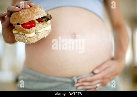 Schwangere Frau mit einem Sandwich. Stockfoto