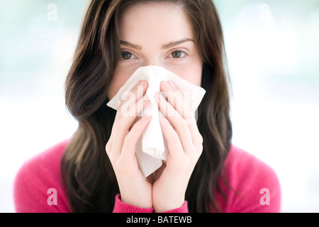 Frau bläst ihre Nase mit Ahandkerchief. Sie ist in ihren Zwanzigern. Stockfoto