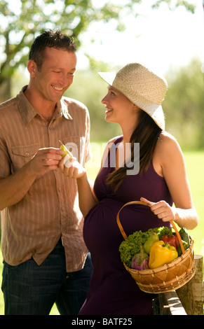 Paare, schwangere Frau hält Korb mit Gemüse Stockfoto