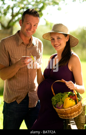 Paare, schwangere Frau hält Korb mit Gemüse Stockfoto