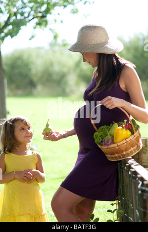 Schwangere Frau mit Kind und Korb mit Gemüse Stockfoto