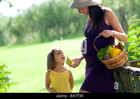 Schwangere Frau mit Kind und Korb mit Gemüse Stockfoto