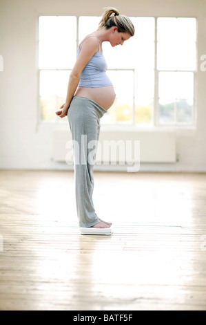 Schwangere Frau mit einem Gewicht von selbst Ona paar Personenwaage. Stockfoto