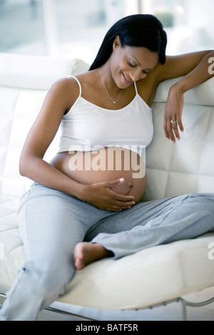Schwangere Frau blickte auf Herswollen Bauch. Sie ist in ihrem dritten Trimester. Stockfoto
