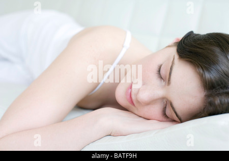 Frau auf einem Bett schläft. Sie ist in ihren Zwanzigern. Stockfoto