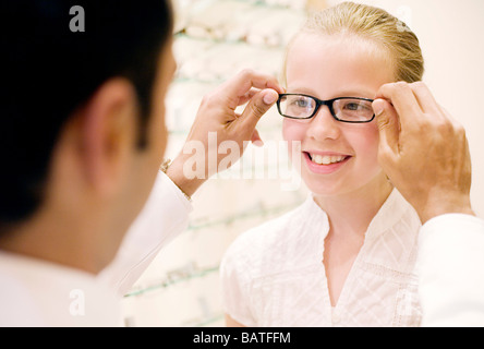 Wählen ein paar Gläser. Optiker helfen, ein Zehn Jahres altes Mädchen ein paar Gläser zu wählen. Stockfoto