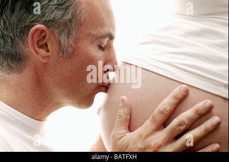 Werdende Eltern. Mann seine schwangere Partnerin geschwollenen Bauch zu küssen. Sie ist in ihrem dritten Trimester. Stockfoto