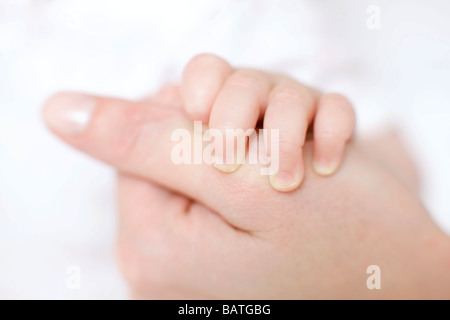 Mutter und Baby. Nahaufnahme von einem 7 Monate alten Baby Mädchen Fingern an ihre Mutter Daumen halten. Stockfoto