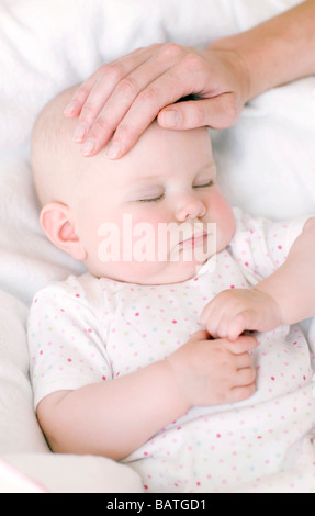 Überprüfen die Temperatur des Babys. Gefühl der Stirn von einem 7 Monate alten Baby-Mädchen zu sehen, ob sie eine Temperatur hat. Stockfoto