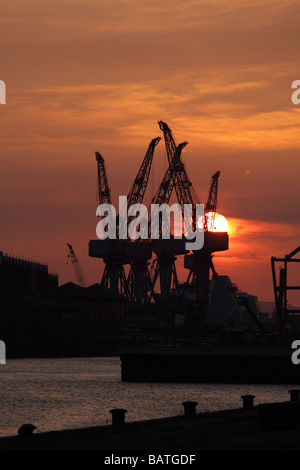 Sonnenuntergang über der alten Krane auf BAE Systeme Werft neben dem Fluss Clyde in Govan, Glasgow, Schottland, Großbritannien Stockfoto