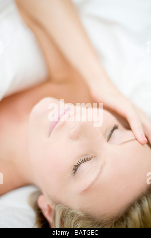 Junge Frau mit Kopfschmerzen hinlegen. Stockfoto