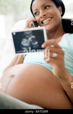 Schwangere Frau am Telefon zu sprechen, halten Sie eine Ultraschalluntersuchung des Kindes Herunborn. Sie ist auf volle Amtszeit. Stockfoto