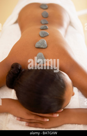 Stone-Therapie. Frau liegend auf den Bauch mit Steinen entlang ihrer Wirbelsäule platziert. Stockfoto