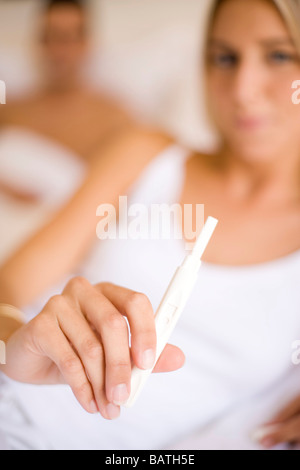 Home Schwangerschaftstests. Junge Frau mit einem Hause Schwangerschaft-Tester. Ihr Partner ist hinter ihr. Stockfoto