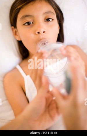 Asthma-Abstandshalter. Mutter hilft ihrer Tochter ein Distanzstück (Kunststoff Kammer) mit einem Inhalator verwenden, während sie im Bett ist. Stockfoto