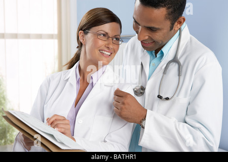 Lächelnd an jeder Otheras Ärzte besprechen sie medizinische Aufzeichnungen. Stockfoto