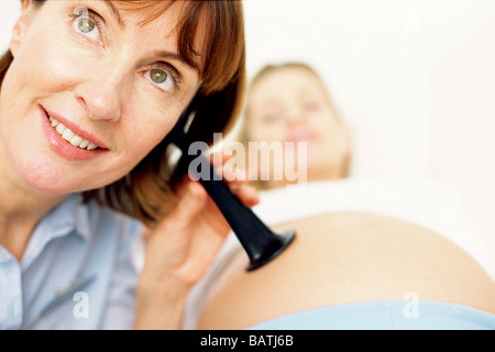 Geburtshilfliche Untersuchung. Hebamme mit einer Earhorn, einer schwangeren Bauch gedrückt Stockfoto