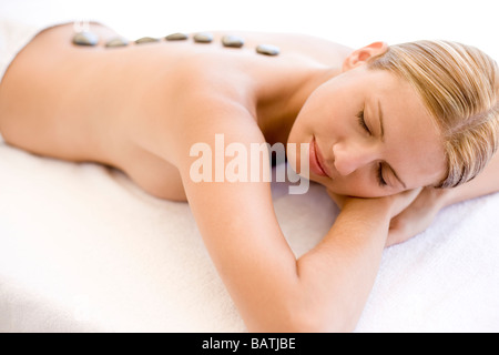 Stone-Therapie. Frau liegend auf den Bauch mit Steinen entlang ihrer Wirbelsäule platziert. Stockfoto