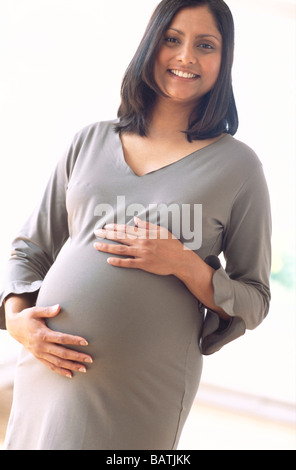 Schwangere Frau lächelnd und halten ihre Hände gegen ihre geschwollenen Bauch. Stockfoto