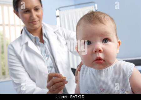 Impfung. 5 Monate altes Baby Mädchen, das einen Impfstoff in ihren Arm aus einer Spritze injiziert. Stockfoto