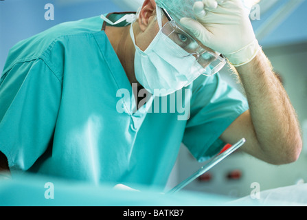 Chirurg drücken seine Hand gegen seine Stirn an Stirn während einer Operation mop. Stockfoto