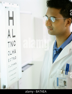 Optiker neben einem Eyechart. Das Auge Diagramm wird verwendet, um eine Person, die Sehschärfe zu testen. Stockfoto